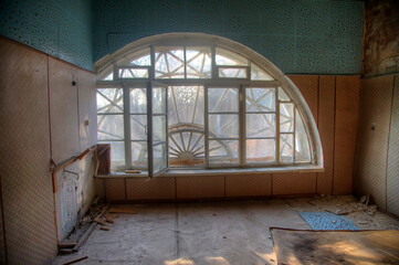 Obraz premium Antique semicircular windows in an old abandoned manor house. Beautiful interior of an old abandoned building. Shabby walls. Landscape outside the window.