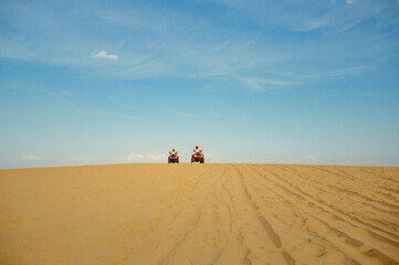 Fototapeta na wymiar Two racers riding on atv in desert, afar view