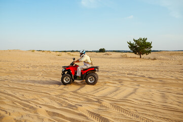 Obraz premium Man in helmet rides on atv in desert sands