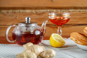 A teapot of transparent strong aromatic tea on a napkin next to ginger and lemon jam