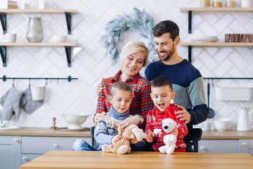 Fototapeta premium . cheerful loving parents stand behind their children and watch them while they play with toys