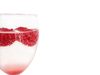 Raspberries in glass of sparkling water on white background ,in close up.