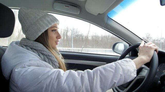 Winter road trip. Profile of a young beautiful girl driver, a young blonde driving a car. Side view. A traveling girl. Happy young Caucasian businesswoman sitting alone in the driver's seat