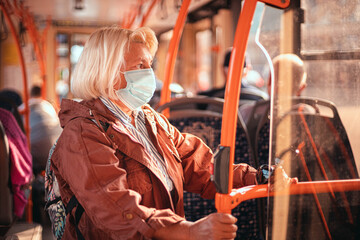 Adult 40-50 year old female passenger wearing a surgical mask on a subway train or bus transport...