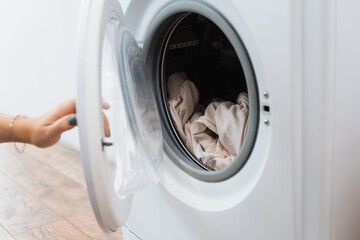 cropped view of woman opening washing machine with laundry.