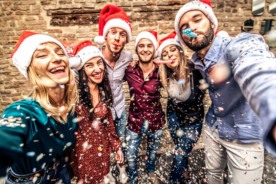 Friends group with santa hats celebrating Christmas taking a selfie - Winter holidays concept with people enjoying time and having fun together