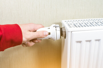 Close up, Man hand adjusting the knob of heating Radiator at home. The valve from the radiator heating. Сoncept of home heating and heat conservation.