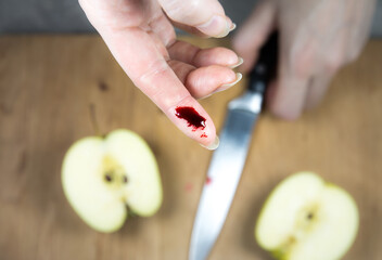 Woman cut her finger with a knife while cooking on the kitchen. Finger with blood, cooking accident.