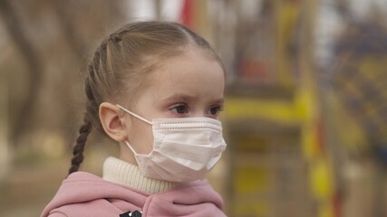 little girl puts on a medical mask on her face, protect child from coronavirus infection, outbreak...