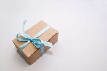 craft gift box tied with a blue bow on a white background with a place for signature