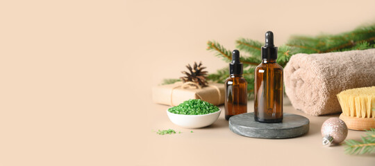 Christmas Spa concept with cosmetic aroma oil, pine cones, evergreen branches on beige background....