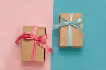 two craft gift boxes tied with pink and blue satin ribbons on pink and blue backgrounds