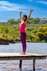 Fototapeta na wymiar A brunette woman doing yoga pose on the edge of a lake at dawn. Body health. Lifestyle. Natural life.