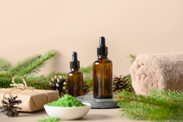 Christmas Spa concept with cosmetic sea salt, essence oil, pine cones, evergreen branches on beige background. Close up. Special offer for beauty saloon.