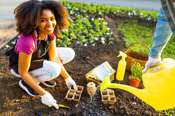beautiful young woman with afro hairstyle working at her garden at sunset spring time outdoors