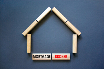 Mortgage broker symbol. Concept words 'Mortgage broker' on wooden blocks near miniature wooden house. Beautiful grey background. Business, mortgage broker concept.