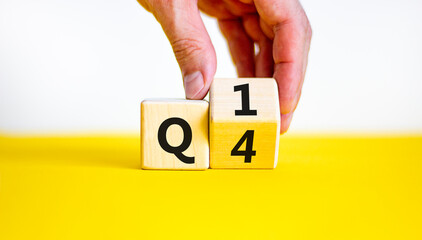 From 4th to 1st quarter symbol. Businessman turns a wooden cube and changes words 'Q4' to 'Q1'. Beautiful yellow table, white background. Business, happy 1st quarter Q1 concept, copy space. - obrazy, fototapety, plakaty