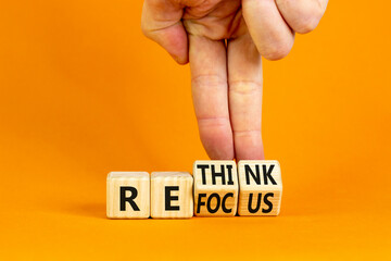 Refocus and rethink symbol. Businessman turns cubes and changes the word 'refocus' to 'rethink'. Beautiful orange table, orange background. Business refocus and rethink concept. Copy space.