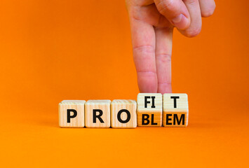 Solving a problem and making profit symbol. Businessman turns wooden cubes, changes the word 'problem' to 'profit'. Beautiful orange background. Business, problem to profit concept. Copy space.