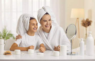 Happy mother and child enjoying morning skin care routine together. Cheerful beautiful mommy and...