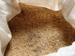 crushed compound feed for farm animals and poultry domans in an open sack made of burlap, feed mixture of bran, wheat, corn and cake for complete feeding of livestock