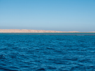 Fototapeta premium Panorama of sea waves against the backdrop of the coast and blue sky.