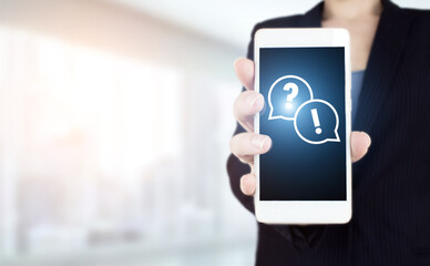 FAQ frequently asked questions concept. Hand hold white smartphone with digital hologram question mark sign on light blurred background. Problem, need of help and advice concept.