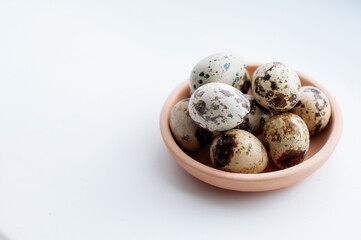 several quail eggs in a clay plate on a white background with a place for the signature