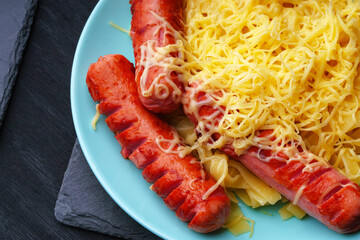 Flat pasta with cheese on a blue plate with fried sausages.