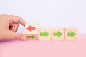 Hand flip over wooden cube block with red arrow facing the opposite direction black arrows, Unique, think different,