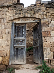 Fototapeta na wymiar Old wooden door opened in the ruined house of the village of the ghost of Gamsutl