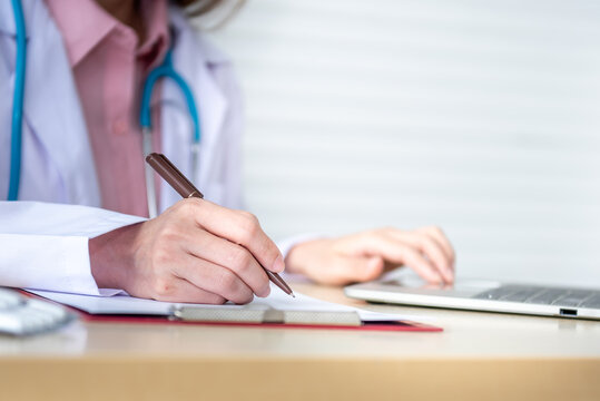 Close up images hand of woman doctor is using a notebook computer, In search of information And write a report, on the desk at workplace, to health care and insurance concept.