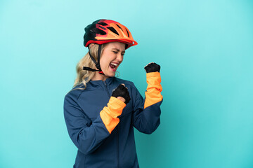 Young cyclist woman isolated on blue background celebrating a victory