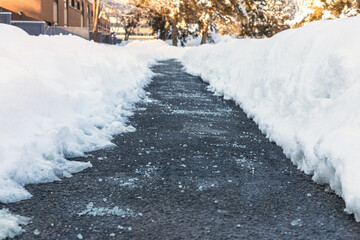 Winter road with salt for melting snow near townhouses