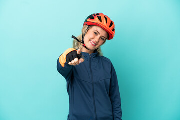Young cyclist woman isolated on blue background pointing front with happy expression