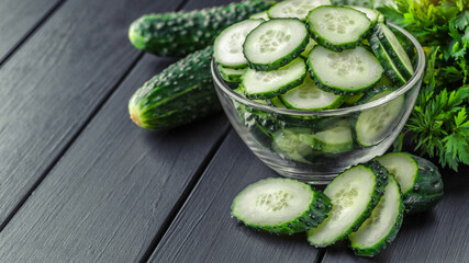 Cucumber on  dark wood texture background.Cucumbers harvest in summer. Cucumbers for salads or canning. Summer vegetables.Slices of fresh cucumbers in a bowl.