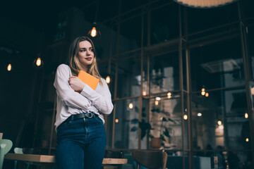 Thoughtful young woman with tablet in modern cafe
