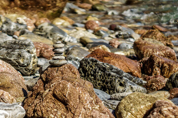 Pyramid stones balance on the sand of the beach. Blue Sea on Background Selective focus, zen stones on sea beach, meditation, spa, harmony, calm, balance concept