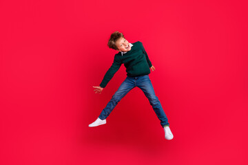 Fototapeta na wymiar Photo of pretty funny school boy wear knitted pullover smiling jumping high isolated red color background