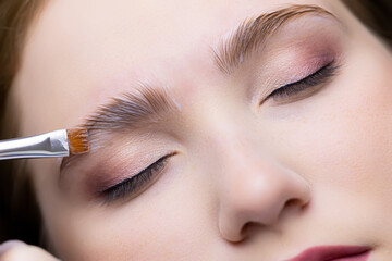 close-up of the eyebrows of the model on which the master applies laminating compositions with a...
