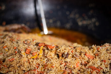A mountain of delicious rice pilaf in an open-air grilled cauldron. Street food at mass events. Background with place for text.