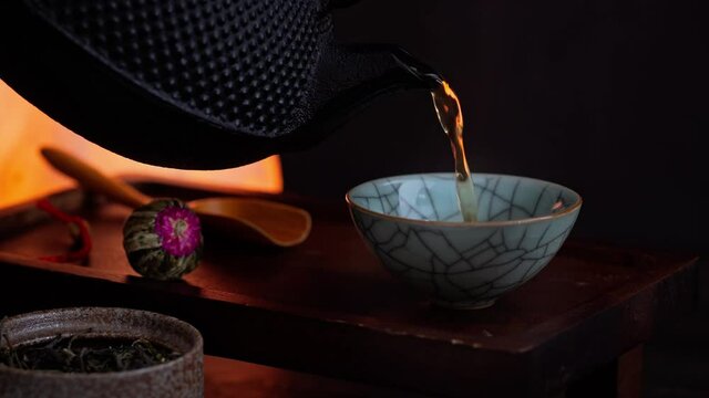 Pouring green tea into traditional oriental cup. Low light