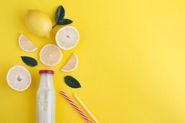 Top view of lemon smoothie in a glass bottle on the yellow background. Copy space.