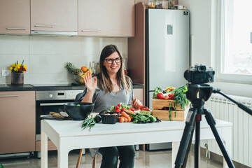 Smiling Woman Recording Video Tutorial Session of Online Cooking Lesson at Home. 
Happy female chef...