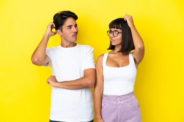 Young mixed race couple isolated on yellow background having doubts while scratching head