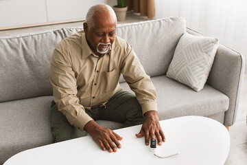 Sick Senior African Man Using Pulse Oximeter Measuring Saturation Indoor