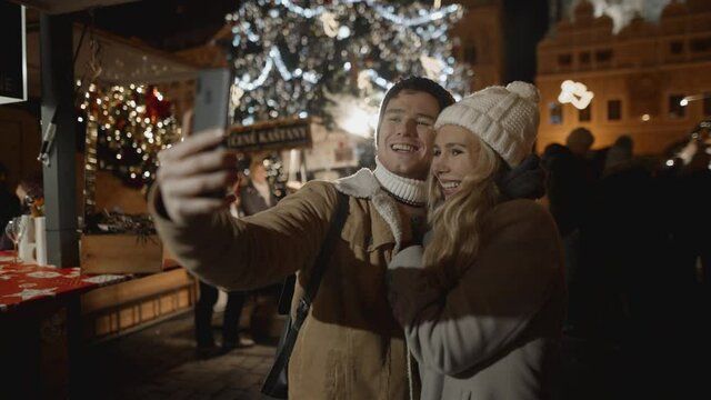 Happy couple taking selfie at night market in Prague. Love, family, christmas, new year, holiday concept. Filmed on RED camera, 10 bit clolor