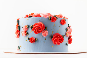 Birthday cake with blue cream cheese frosting decorated with red flowers on the white background. Happy 70 years anniversary