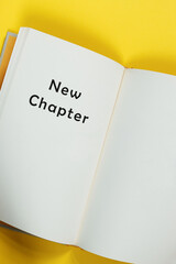 New chapter written in open yellow book page. New beginning concept.