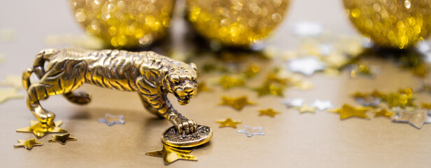 Banner bronze figure of a tiger with a coin - the symbol of the Chinese new year 2022 on a background of stars, golden shiny balls, copy space. Wishes of good luck, financial well-being and wealth